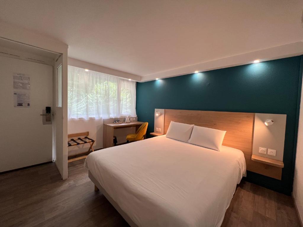 色当Kyriad SEDAN的卧室设有一张白色大床和绿色的墙壁
