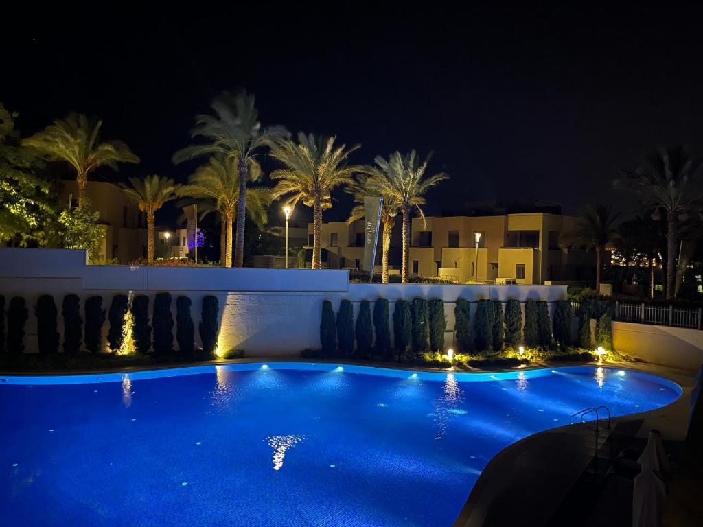 亚喀巴Al Raha Village - Aqaba的棕榈树和建筑的夜间游泳池