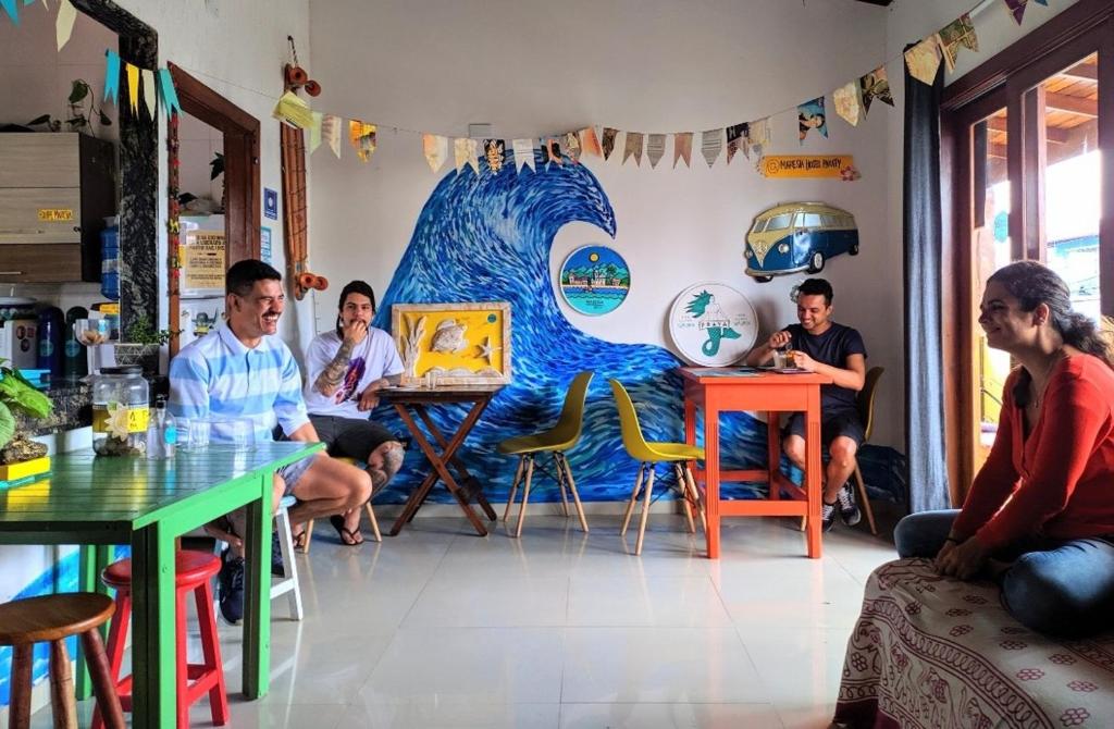 帕拉蒂Maresia Hostel Paraty BR的一群人坐在一个房间里,画着一幅波浪