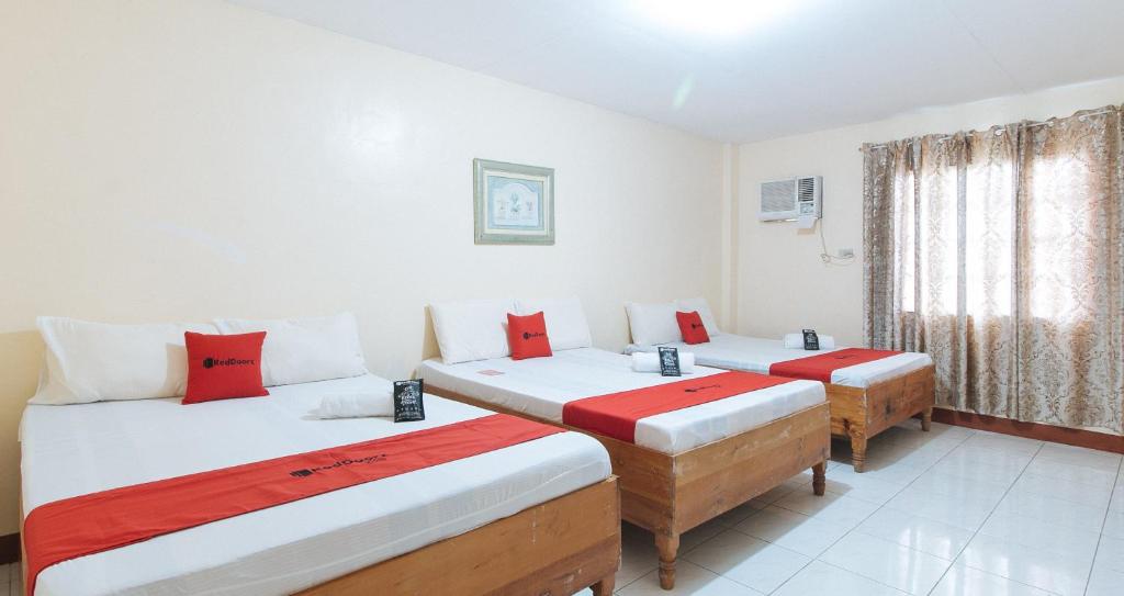 UrdanetaRedDoorz @ Goldland Spring Resort Urdaneta City的客房配有两张带红白色枕头的床。