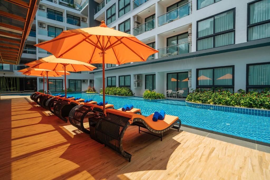 卡塔海滩Wekata Luxury的游泳池旁一排带遮阳伞的椅子