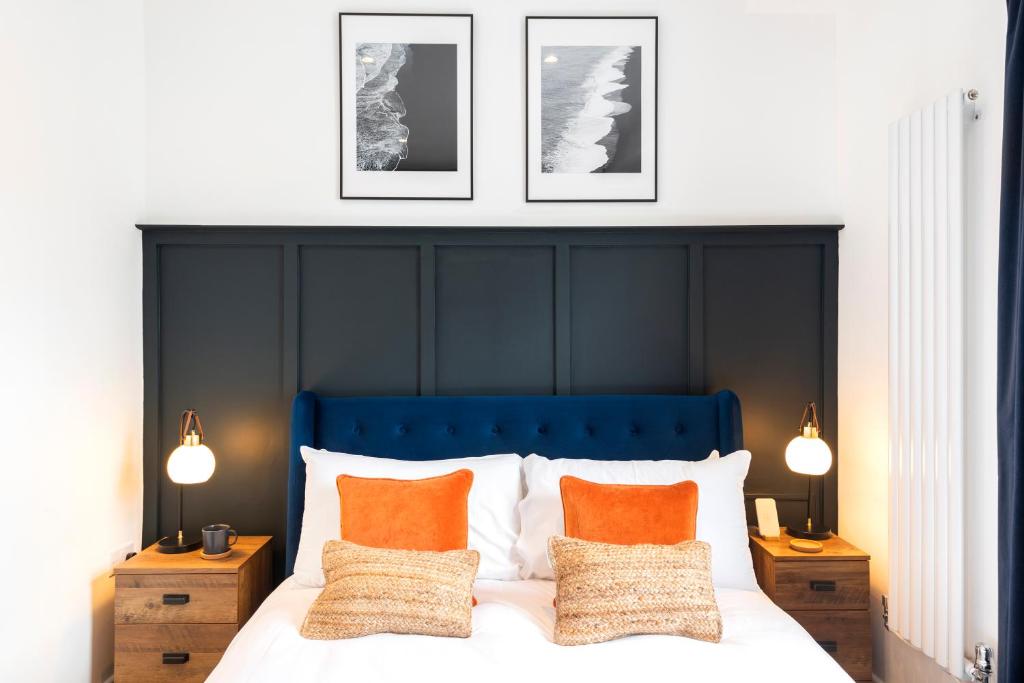 纽波特Crescent Apartments的一张带蓝色床头板的床和墙上的三张照片