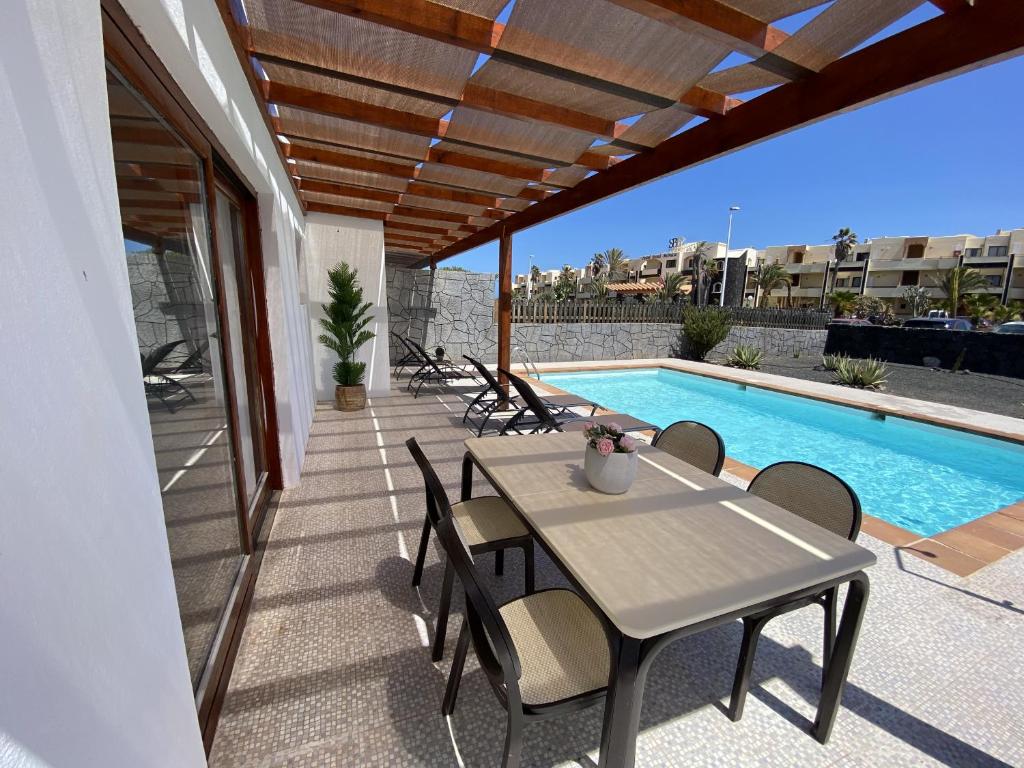 普拉亚布兰卡Villalia Capri的游泳池旁带桌椅的天井