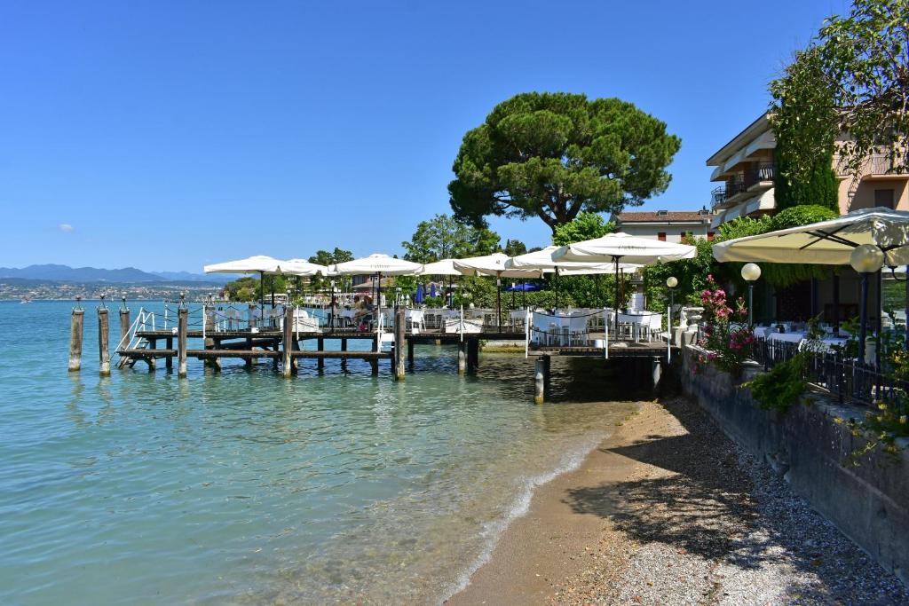 西尔米奥奈佩斯酒店的水面上带桌子和遮阳伞的码头