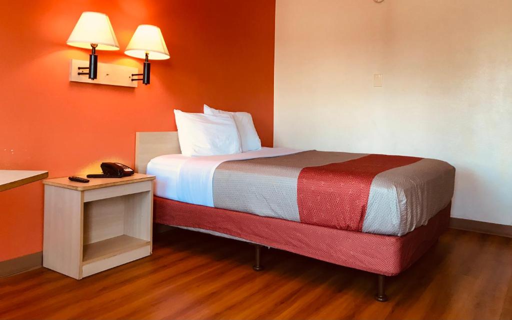 麦迪逊高地Travelodge by Wyndham Madison Heights MI的橙色墙壁的房间里一张小床