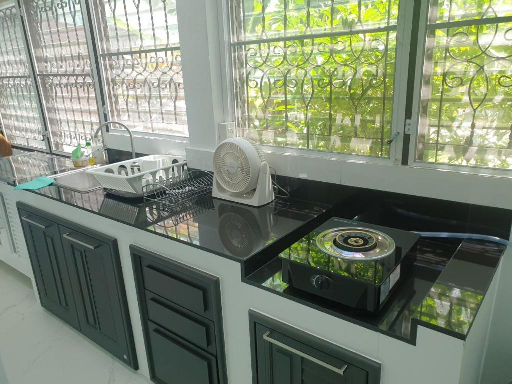 七岩Cha-am Beach Vacation Home的厨房配有带风扇和窗户的柜台。