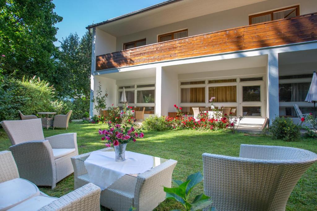 沃尔特湖畔佩莎赫Villa Gabriela的庭院配有椅子和一张带花瓶的桌子