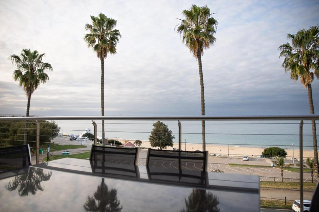 莫塞尔湾Santos Seaview Apartment的阳台享有海滩和棕榈树的景致。