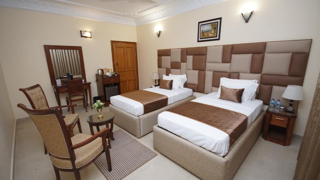 卡拉奇World Inn Karachi的酒店客房,配有两张床和椅子