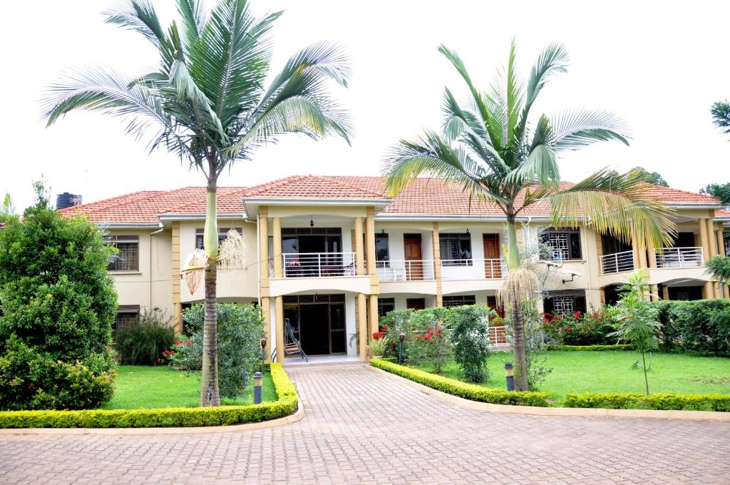 坎帕拉Olive Gardens Hotel Kampala的一座棕榈树大房子前面