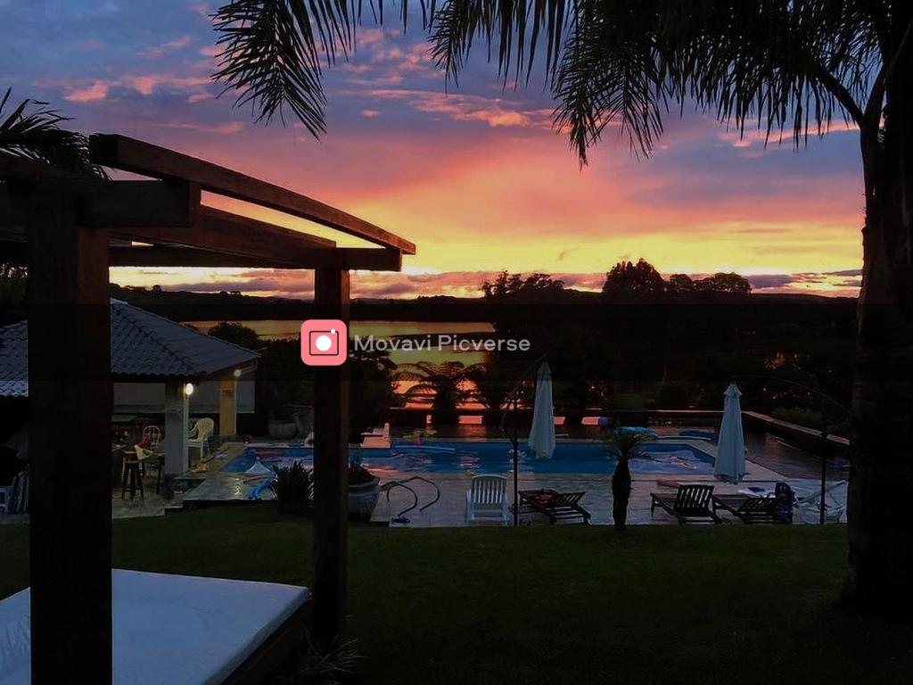 拉热斯Paraíso do Salto的享有游泳池的景色,背景是日落