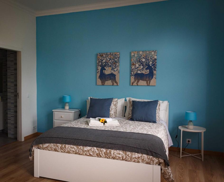 辛特拉Flor&Fidalgo Guest House的一间蓝色卧室,配有一张床,墙上有三幅画作