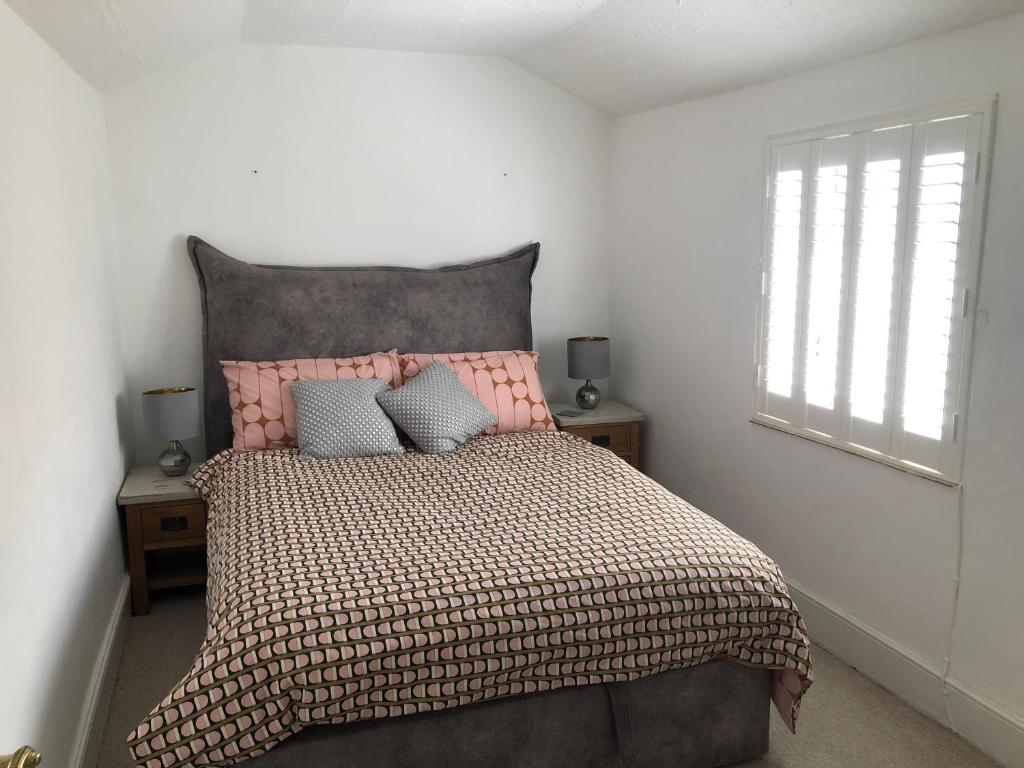 汤顿Homely Victorian Terraced Town House with Parking.的一间卧室配有一张带粉红色床头板的床和窗户。