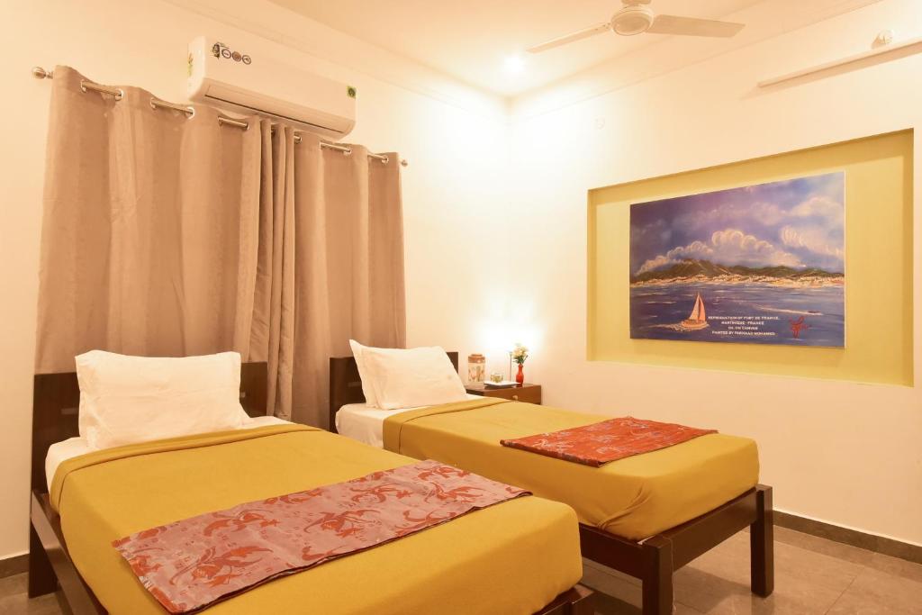 蓬蒂切里BHARATHI RESIDHOME的一间设有两张床的客房,墙上挂着一幅画