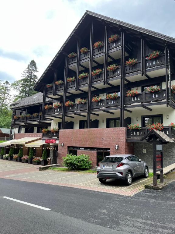 锡纳亚Casa Iris-Hotel & Restaurant的停车场位于带阳台的大楼前