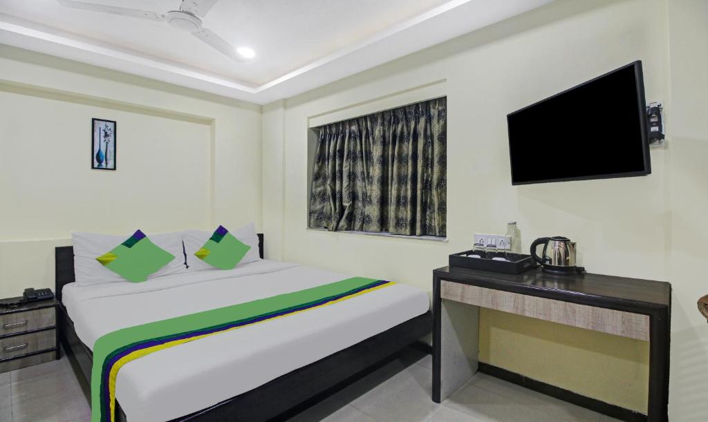 加尔各答Treebo Trend Naman's Inn的一间卧室配有一张床、一张书桌和一台电视