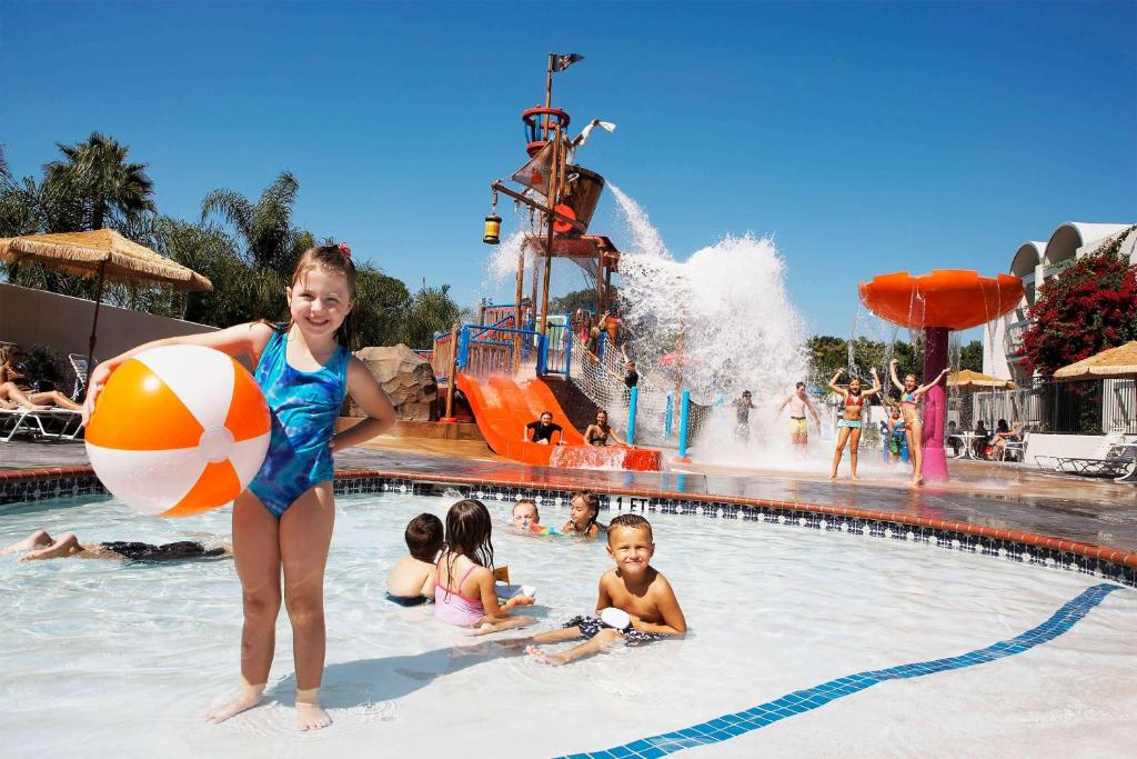 安纳海姆阿纳海姆豪生国际酒店和水上乐园的在一个水上公园的游泳池里抱着沙滩球的女孩