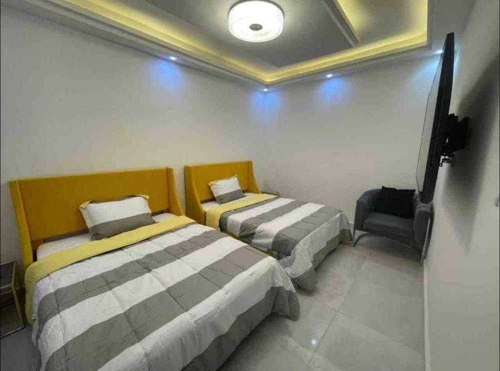 达喀尔Appartement Luxe idéalement situé à Dakar的配有电视和椅子的客房内的两张床