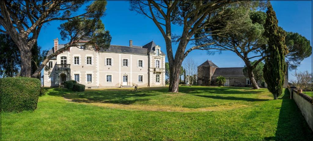 Rochefort-sur-LoireVignoble Château Piéguë - winery的一座大白色房子,在院子里种有树木