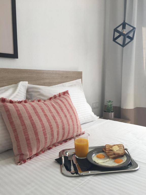 克拉法吉亚Blue View Suites的床上的早餐托盘,包括鸡蛋和橙汁