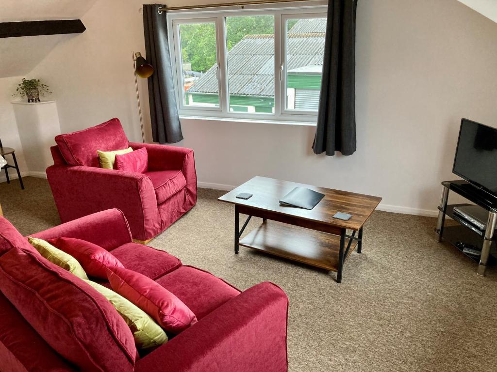 温德米尔布里斯科自助式公寓酒店的客厅配有2把红色椅子和咖啡桌