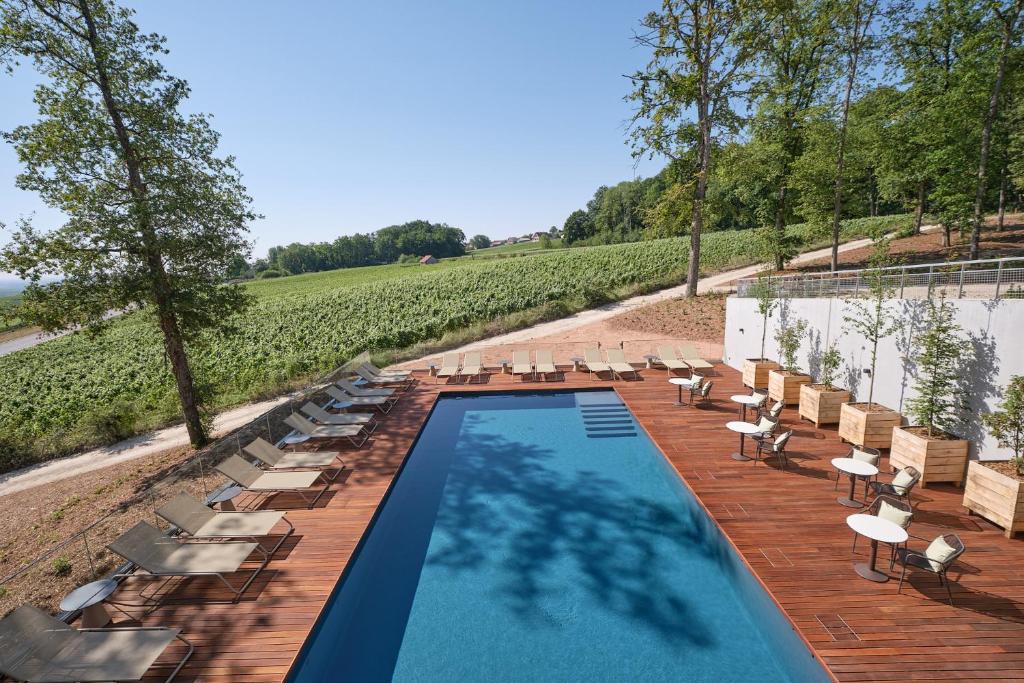 MutignyLOISIUM Wine & Spa Hotel Champagne的一个带桌椅的游泳池和一个葡萄园