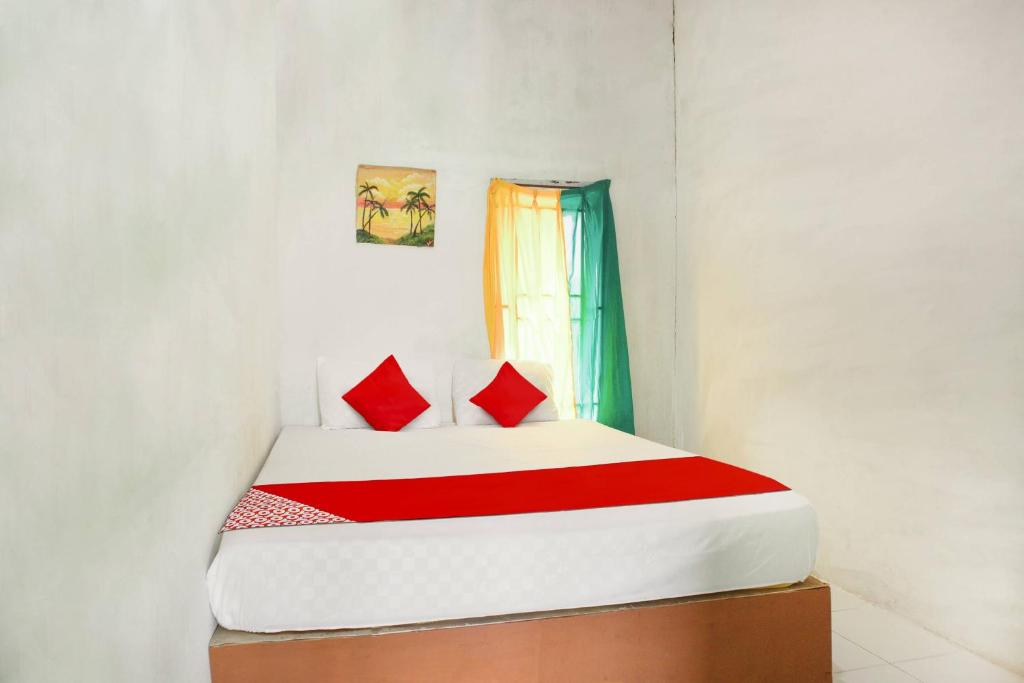 坤甸OYO 91051 Penginapan Pondok Ratu 354的一间卧室配有一张带红色枕头的床和一扇窗户