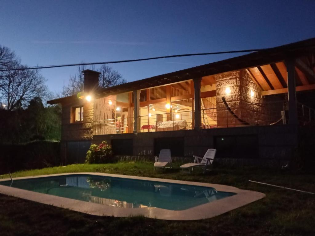 Parada de AchasLobetios - Casa rural的一座晚上设有游泳池的房子