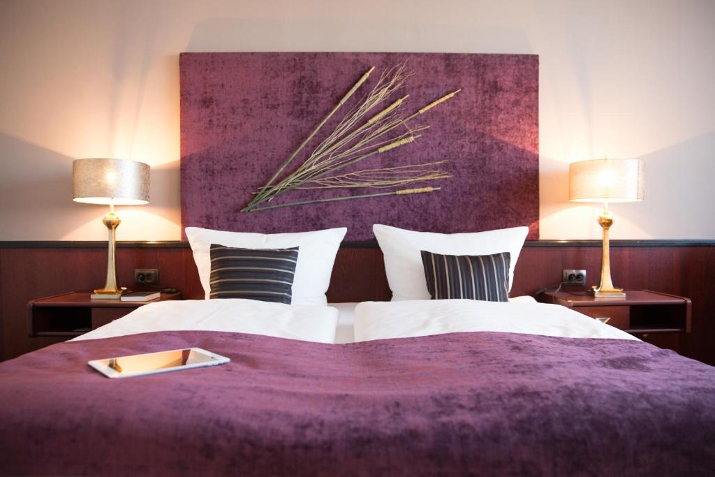 魏斯瓦塞尔水晶酒店的一间卧室配有一张带两盏灯的紫色床