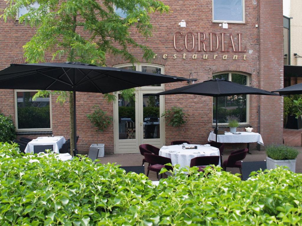 奥斯Boutique Hotel Cordial的餐厅前的两张桌子和遮阳伞