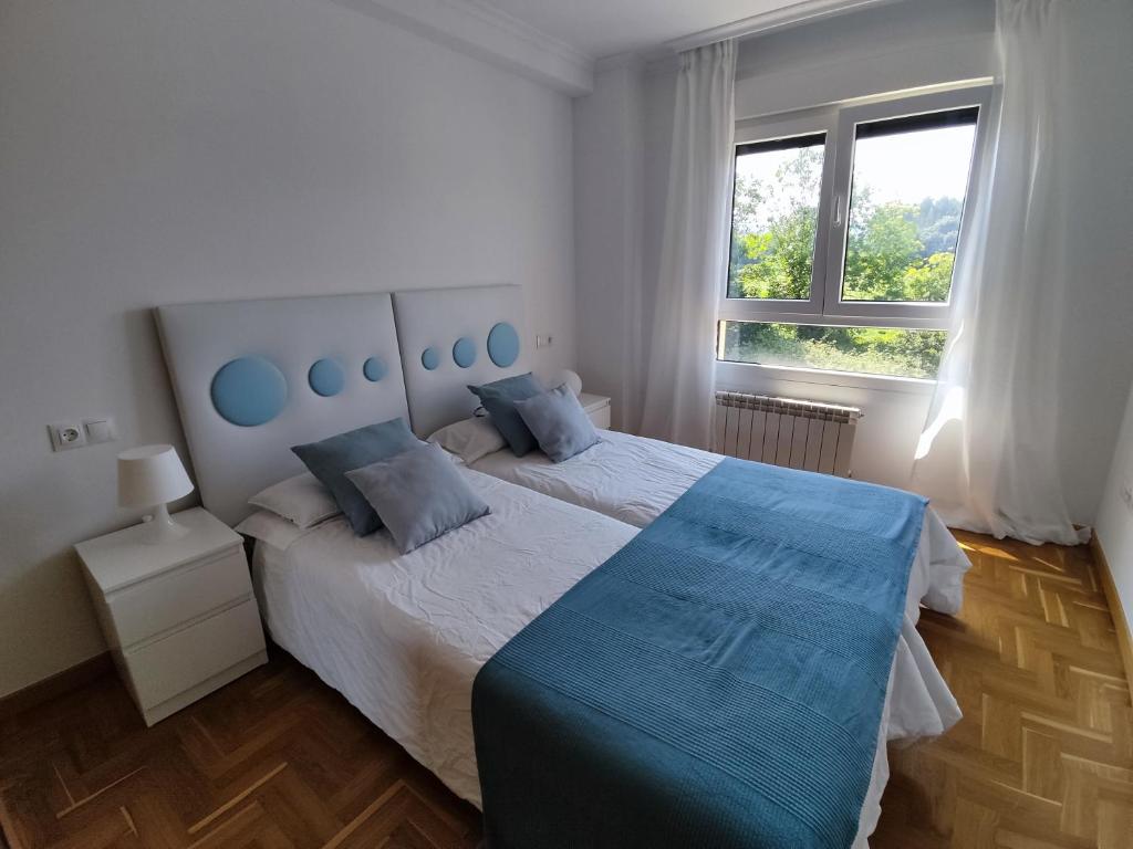 Posada de LlanesApartamento MAR y MONTAÑA ASTURIAS的一间卧室配有一张带蓝色枕头的大床