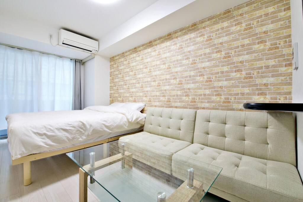 东京Green Sea Oshiage的一间带沙发和砖墙的卧室