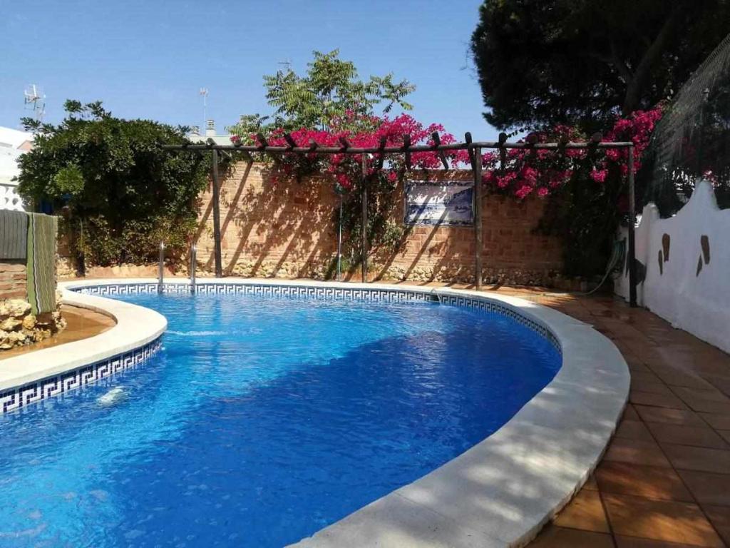蓬塔翁布里亚Casa Marquesa的蓝色的游泳池,设有围栏和粉红色的鲜花
