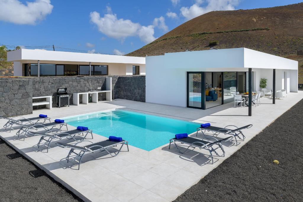 蒂亚斯Villa Ainara的别墅 - 带带椅子的游泳池和房屋