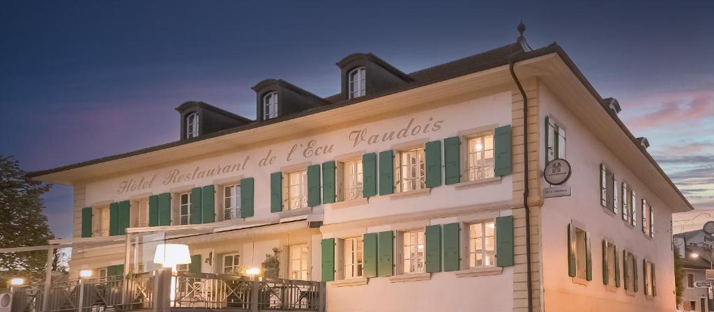 伯尼安Boutique Hôtel de l'Ecu Vaudois的一座白色的大建筑,设有绿色百叶窗