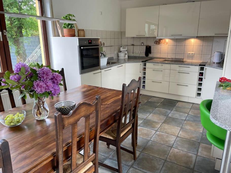 蒙绍Behagliches Haus mit Kamin的厨房配有带椅子的木桌和紫色鲜花