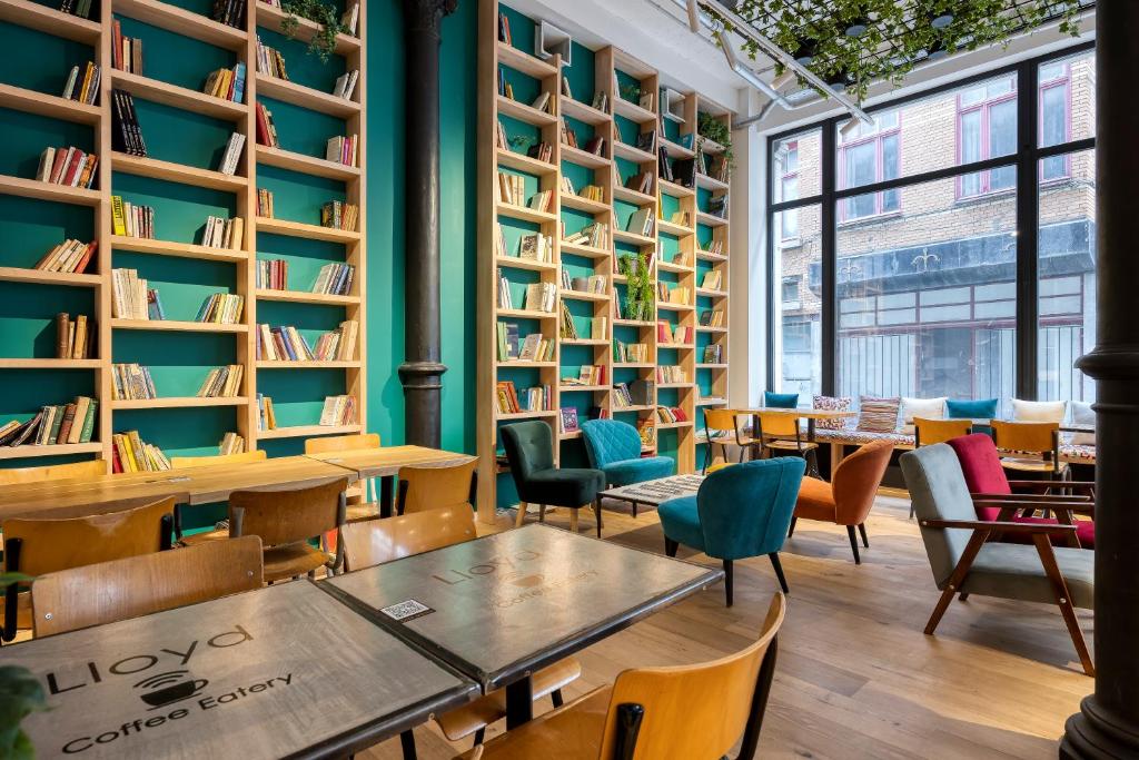 布鲁塞尔阿利斯大酒店的图书馆配有桌椅和书架