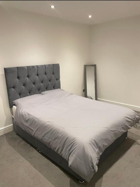 普拉姆斯特德Tee's apartments的一间卧室配有一张大床和灰色床头板