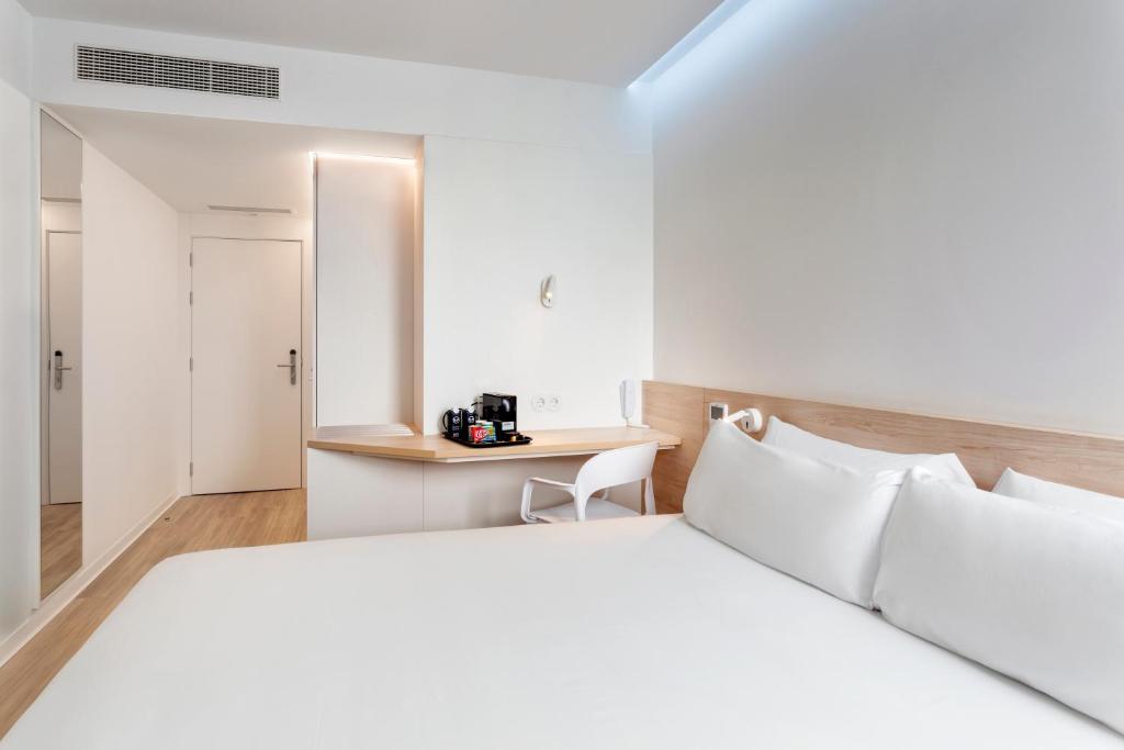 维拉诺瓦-德法马利B&B HOTEL Famalicão的卧室配有白色的床和书桌