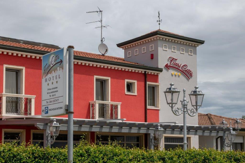 斯坦盖拉Hotel Fuori Città的一座红色和白色的建筑,前面有标志
