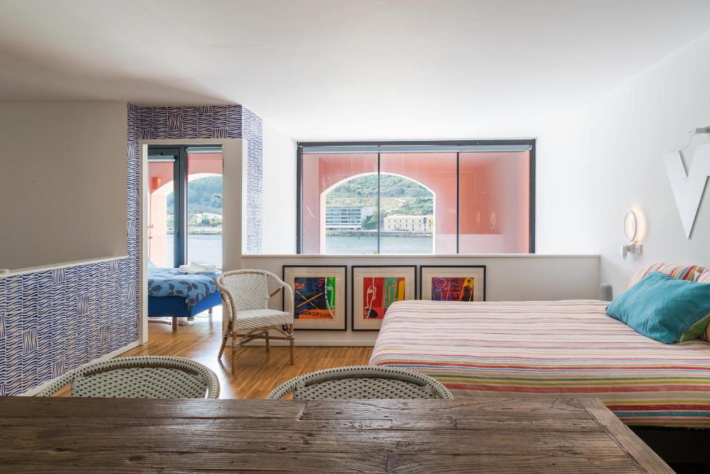 波尔图Porto Insight Apartment River View - Pool & Garage的一间卧室配有一张床铺、椅子和一张桌子