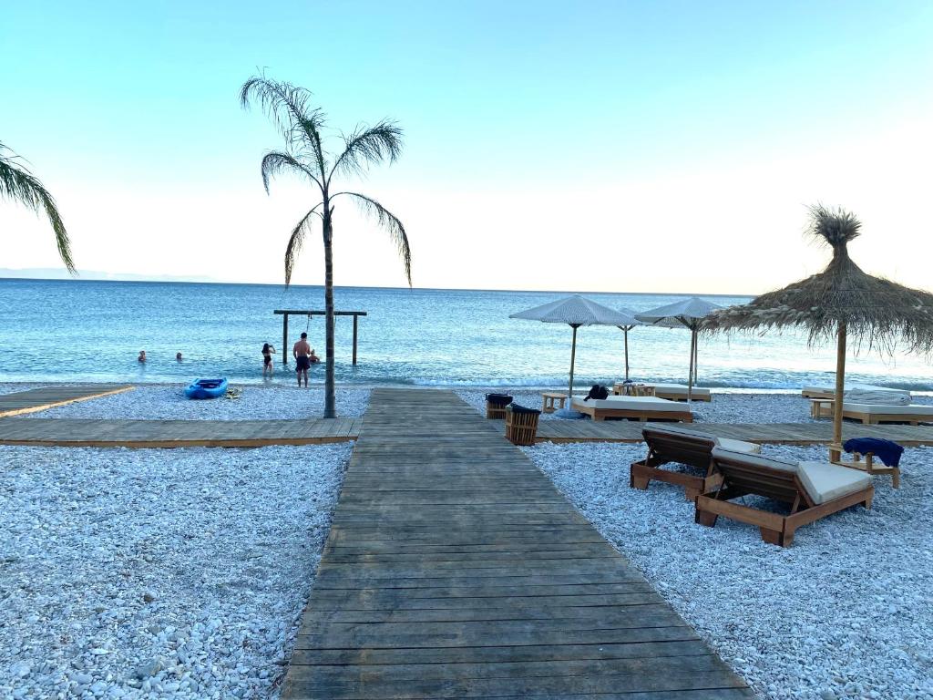 博尔什Maison Bellevue - 2 bdrm villa in Borsh beach的海滩上设有长椅和遮阳伞,还有大海
