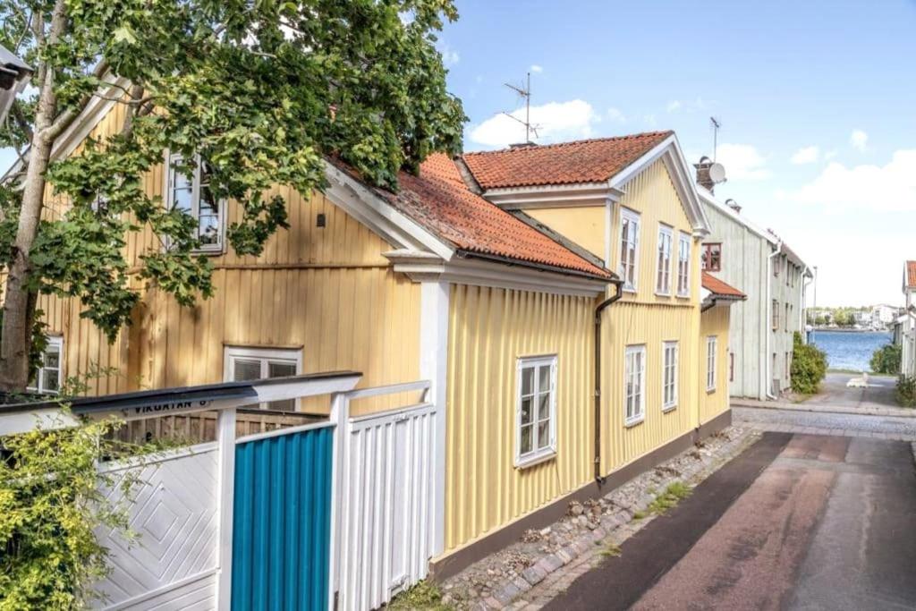 韦斯特维克Central lägenhet i nyrenoverat 1700-talshus的街道旁的黄色房子,有白色的围栏