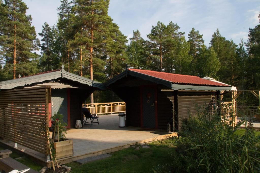 卡尔斯塔德Timber cottages with jacuzzi and sauna near lake Vänern的几间木制小屋,配有甲板