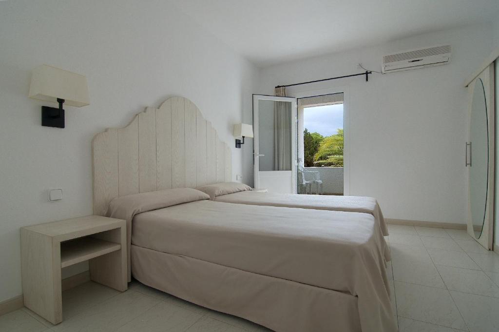 埃斯普霍斯卡普里旅舍的白色的卧室设有一张大床和一个窗户