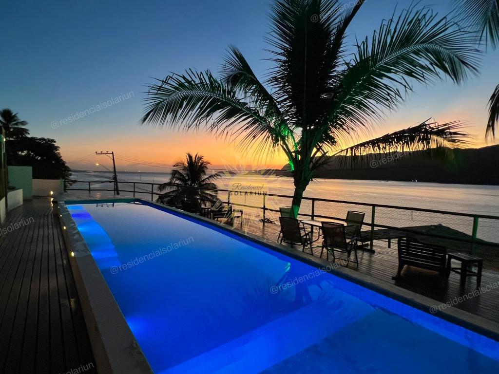 伊利亚贝拉Residencial Solariun Ilhabela的日落时分享有海洋美景的游泳池