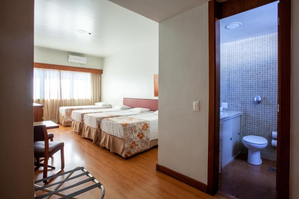 贝洛奥里藏特Hotel Nacional Inn Belo Horizonte的酒店客房设有三张床和一间浴室。