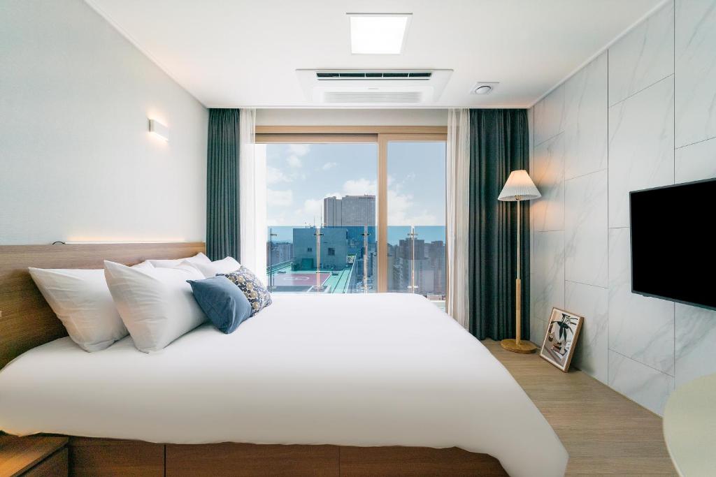 济州市Urbanstay Jeju Airport的卧室设有一张白色大床和大窗户