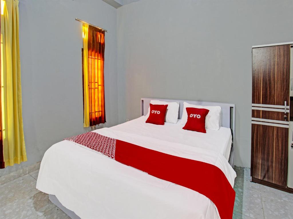 萨萨克OYO 91210 Hotel J3的卧室配有带红色枕头的大型白色床