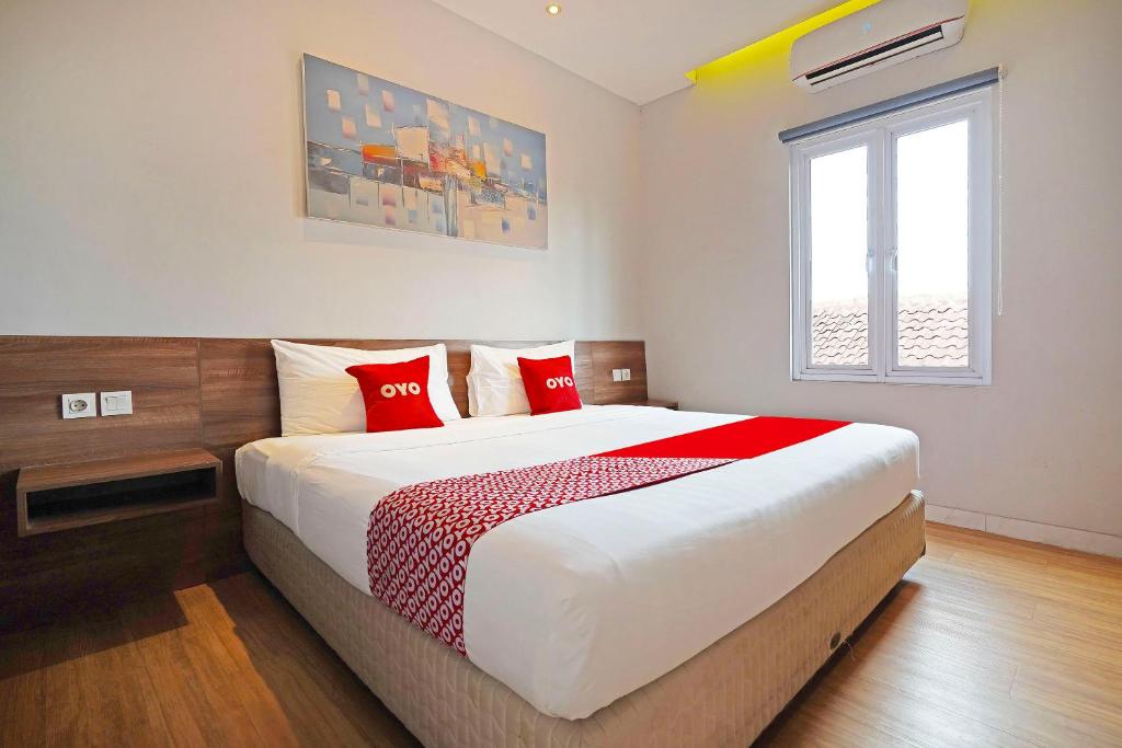 万隆Super OYO Collection O 91472 The Regia Dago的一间卧室配有一张带红色枕头的大床
